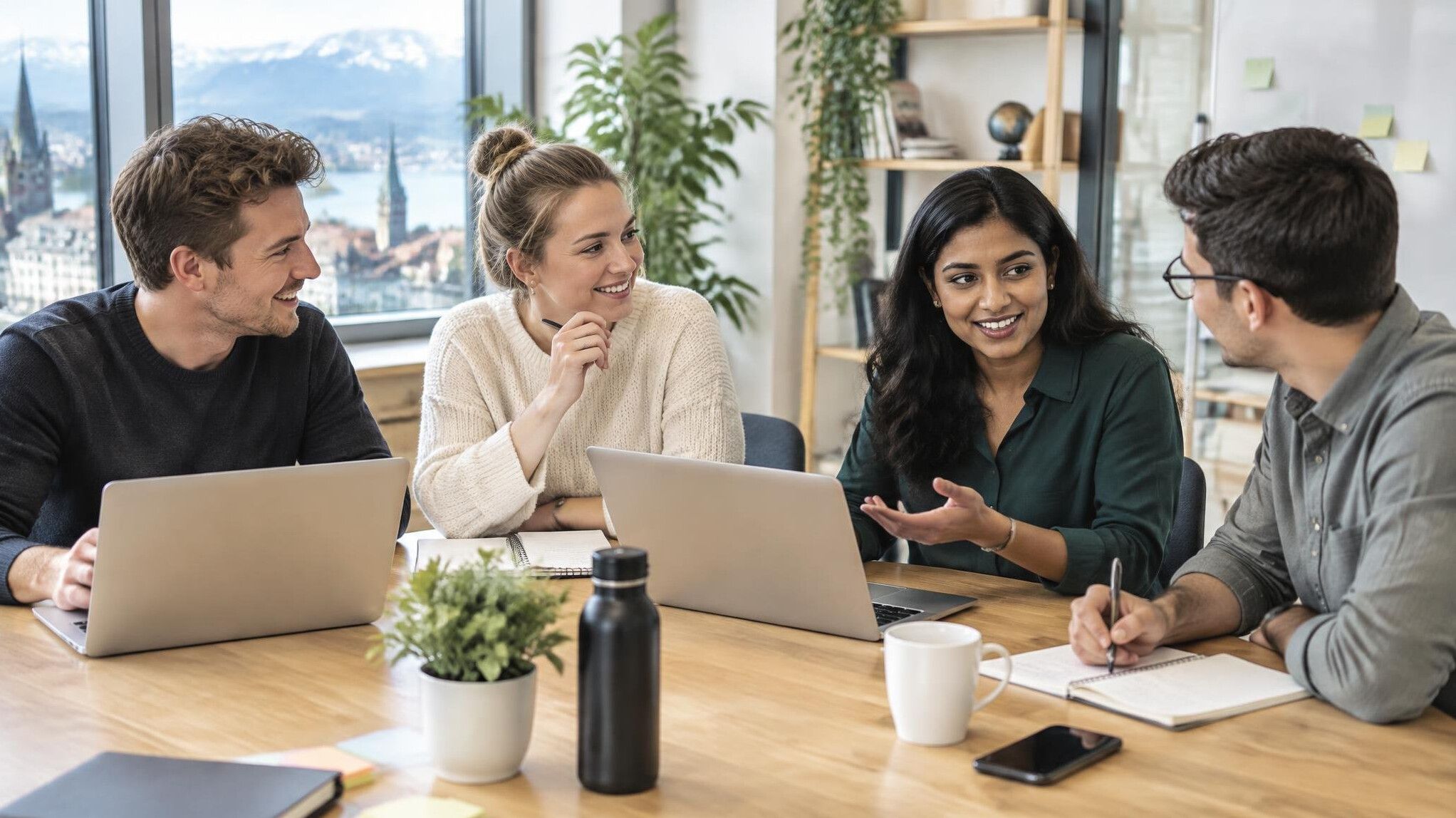 Small team collaborating around a table with laptops